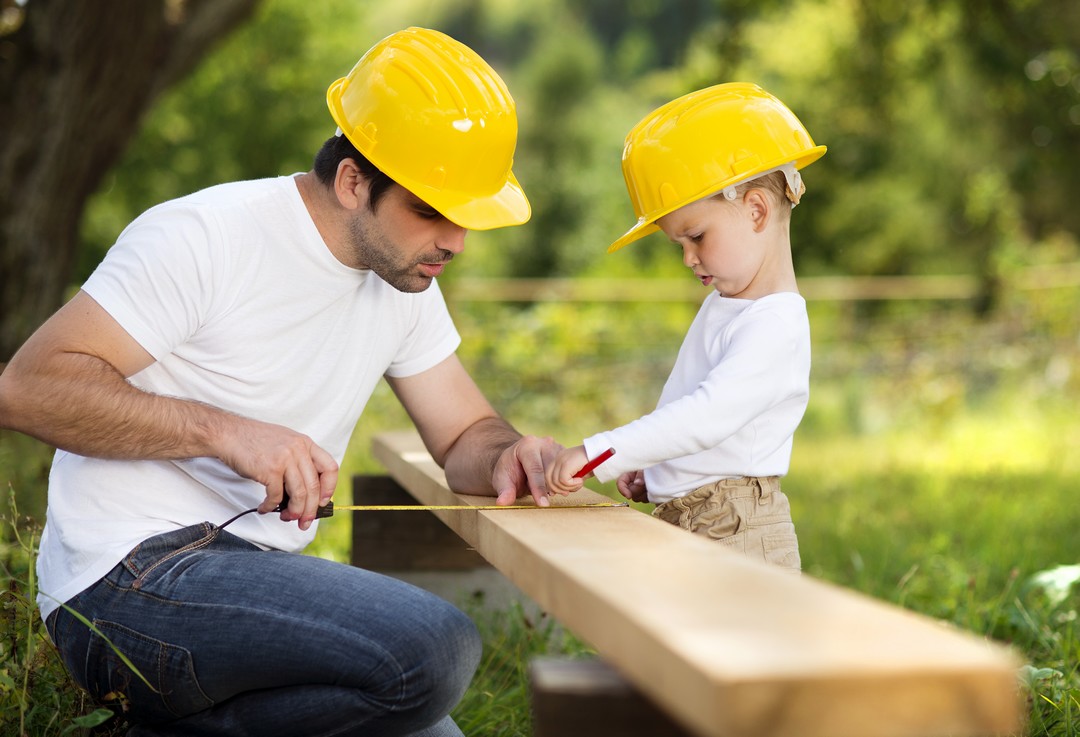 Un père et un fils en train de prendre des mesures sur une planche de bois.